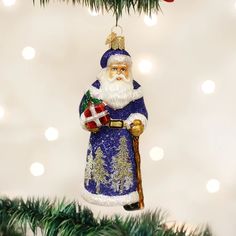 a christmas ornament with a santa clause holding a present under a pine tree