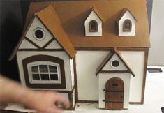 a hand is pointing at a model house