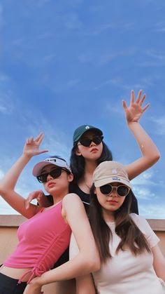 three young women standing next to each other with their arms in the air and one holding her hand up