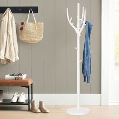 a coat rack with shoes on it next to a wooden bench and white coat hanger