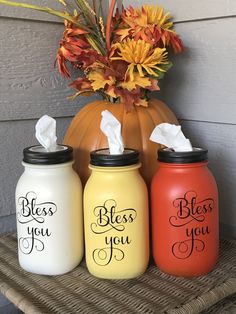 three painted mason jars sitting on top of a table next to a vase with flowers