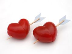 two red heart shaped lollipops with toothpicks in the shape of hearts