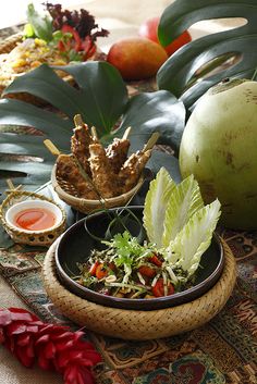 there are many different foods in bowls on the table with fruit and vegetables around them