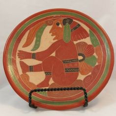 an orange and green plate with designs on the front is sitting on a white surface