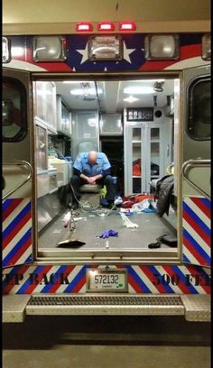 a man sitting in the back of a firetruck looking at something on the ground