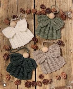 three crocheted hats with bows and pine cones on the ground next to them