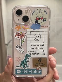 someone is holding up their phone case with stickers on it and there are other things in the back