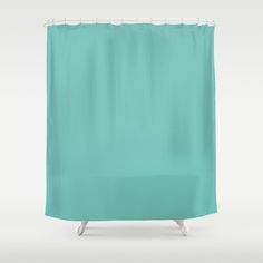 a turquoise shower curtain with white trim on the bottom and side, in front of a gray background