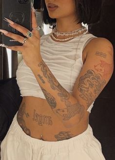 a woman with tattoos on her arm holding a cell phone