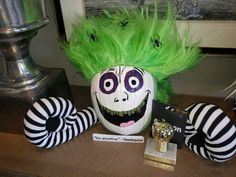 a creepy doll with green hair sitting on top of a table next to other decorations