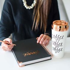 a woman sitting at a table with a coffee cup and notebook in front of her