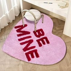 a pink bathroom rug with the word wine on it and a chair in front of it