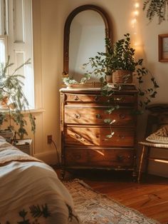 a bedroom with a dresser, mirror and plants on the side table in front of it