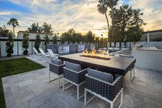 an outdoor fire pit surrounded by lounge chairs and palm trees in the background at sunset