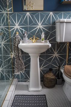 a white pedestal sink sitting next to a toilet in a bathroom on top of a black and white tile floor