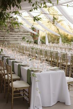 tables set up for an event with white linens and greenery