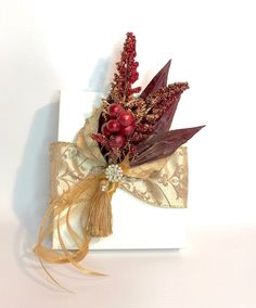 a white box with some red berries on top of it and gold ribbon around the edge