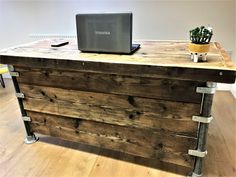 a laptop computer sitting on top of a wooden desk next to a potted plant