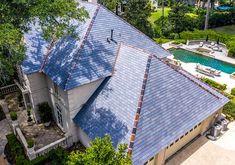 an aerial view of a house with a pool in the back ground and trees surrounding it