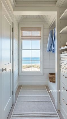 an empty white room with a window, rug and towels on the shelf next to it