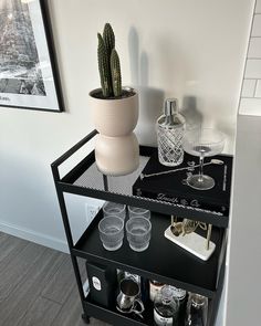 a black shelf with glasses and a cactus on top