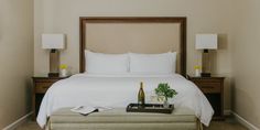 a hotel room with a bottle of champagne on the bed and a tray full of books