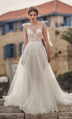 a woman in a white wedding dress standing on steps with her hands behind her back