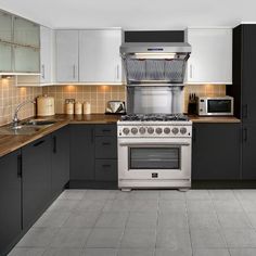 a kitchen with black and white cabinets, stainless steel stove top oven and counter tops