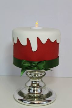 a red and white cake with a green bow on it's top sitting on a silver plate