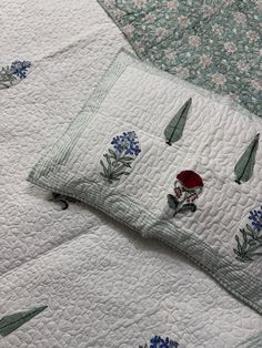 two pillows with embroidered flowers on them are laying next to each other in the same pattern