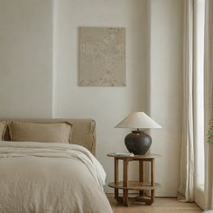 a bed sitting next to a lamp on top of a wooden table in a bedroom