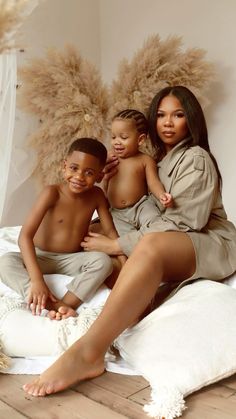 two children and an adult sitting on a bed in front of some fluffy furs