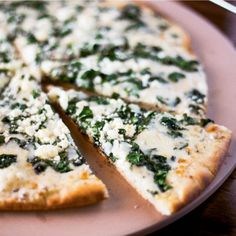 a close up of a pizza on a plate with cheese and spinach toppings