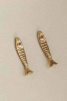 The detail in our Pisces earrings bring the ocean to its wearer, honoring the relation between sea and land by offering a portrait in earth's precious metals and stones. This fish is unique in its aversion to water. Please remove your Pisces Studs before bathing or taking a dip to protect the stone's setting. Gold vermeil or solid 14k fish with precious stone eyes. 1" in length. Sold as a single earring or a pair. The 14k Pisces studs are paired with solid 14k gold earnuts. Rubies speak to our i Gold Fish Earrings, Fish Earing, Colorful Piercings, Jewelry Illustration Art, Sardine Earrings, Piercing Ideas Unique, Pisces Earrings, Ear Scape, Sea Jewellery