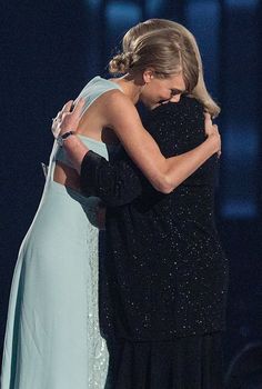 two women hugging each other on stage