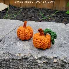 two crocheted pumpkins sitting on top of a rock