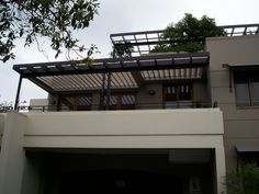 an apartment building with a balcony and metal railings on the upper level, overlooking trees