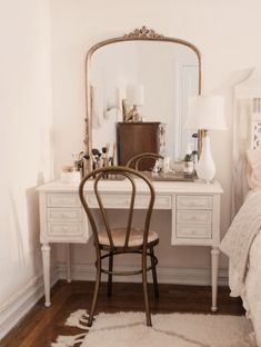 a bedroom with a chair, desk and mirror