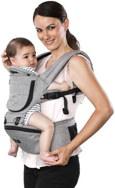 a woman is holding a baby in a grey sling that's attached to her chest