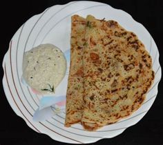 two pieces of flat bread on a plate next to a bowl of dip and pita bread