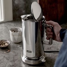 a person holding a coffee pot on top of a counter