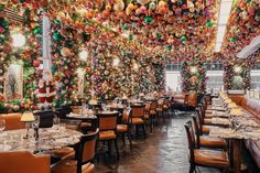 a dining room with tables and chairs covered in christmas decorations, hanging from the ceiling