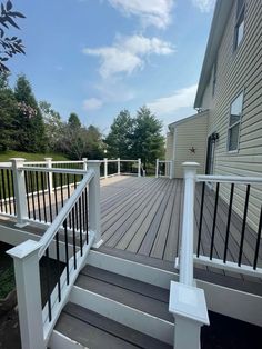 a wooden deck with white railings next to a house