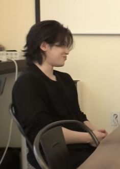 a woman sitting at a table in front of a laptop computer