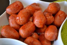 a white bowl filled with red meatballs on top of a green place mat,