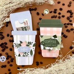 two coffee cups sitting next to each other on top of a table with coffee beans