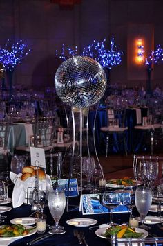 a table set up for a party with disco ball centerpieces and place settings