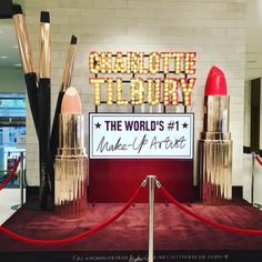 there is a display with lipstick and makeup products on the red carpet in front of it