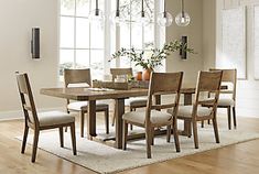 a dining room table with six chairs and a rug on the floor in front of it