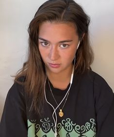 a girl with ear buds on her ears looking at the camera while wearing headphones